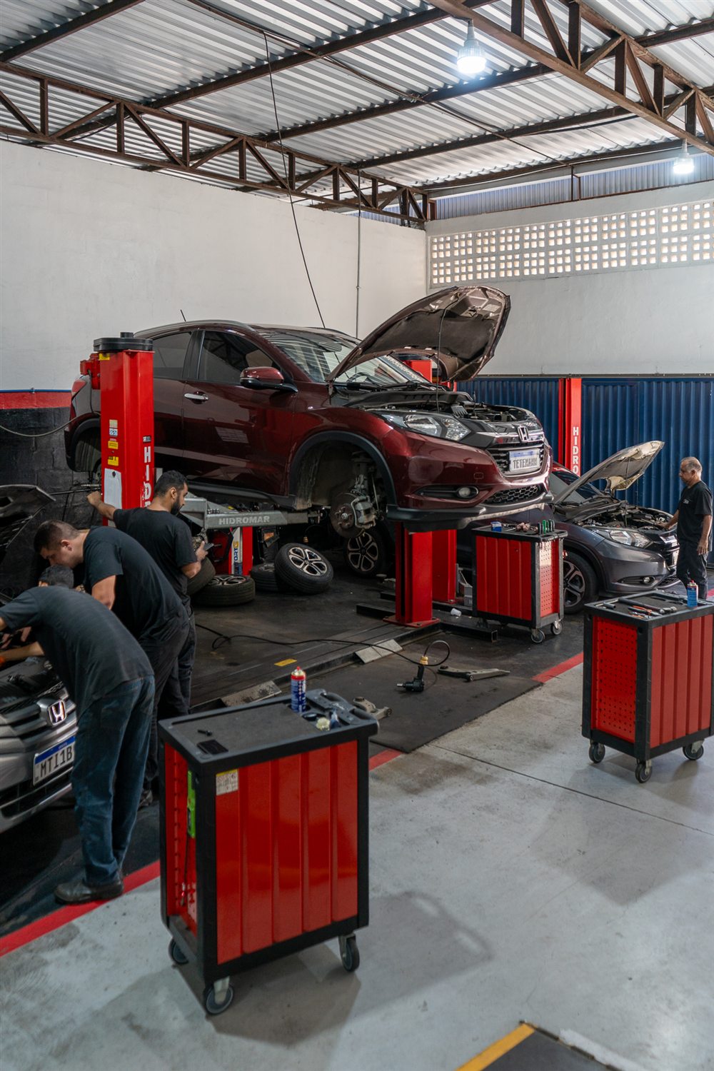 Mecânicos da Tetemann atendendo um Honda HR-V no elevador, com carrinhos de ferramentas vermelhos